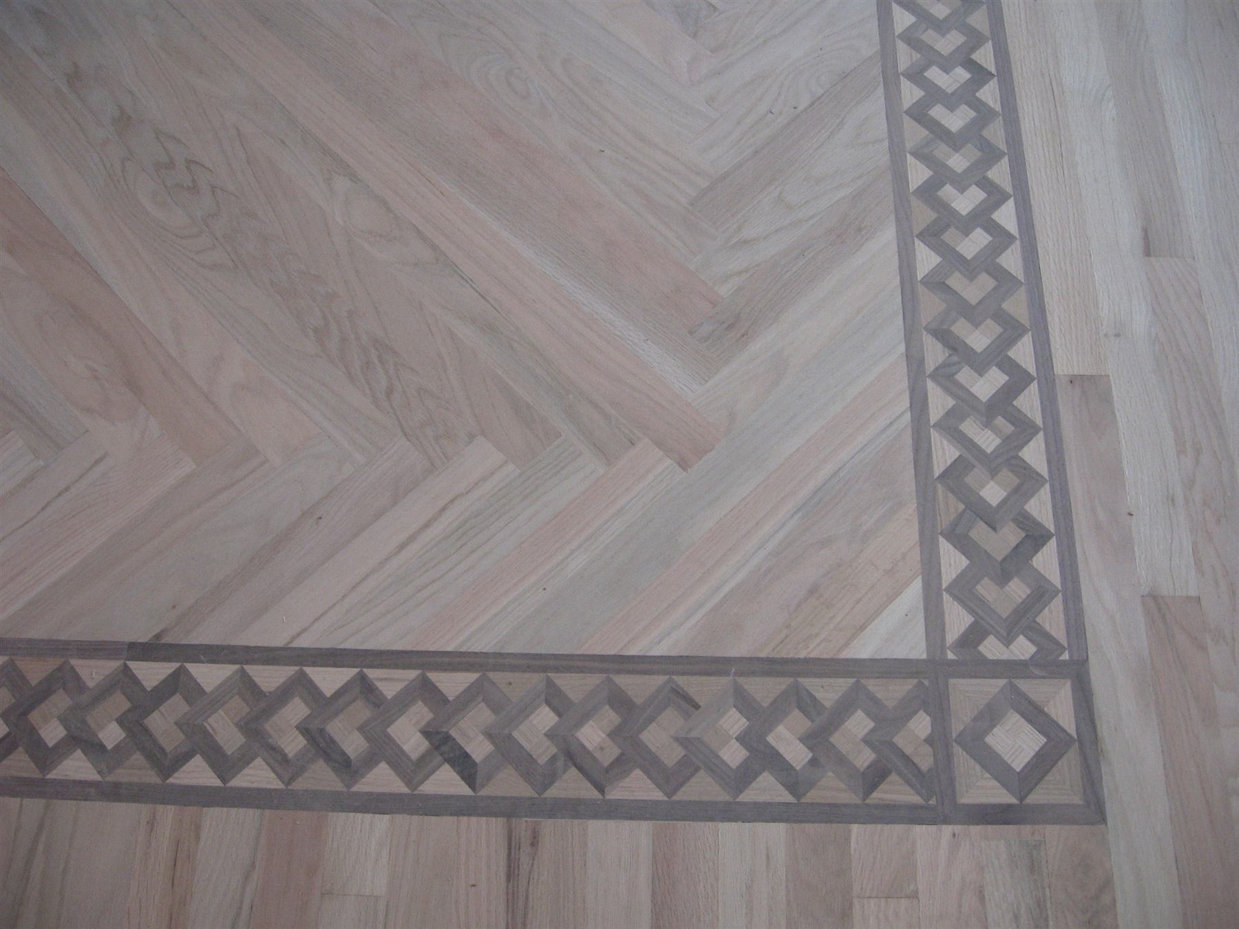 Detail of a custom hardwood floor with a decorative herringbone inlay border